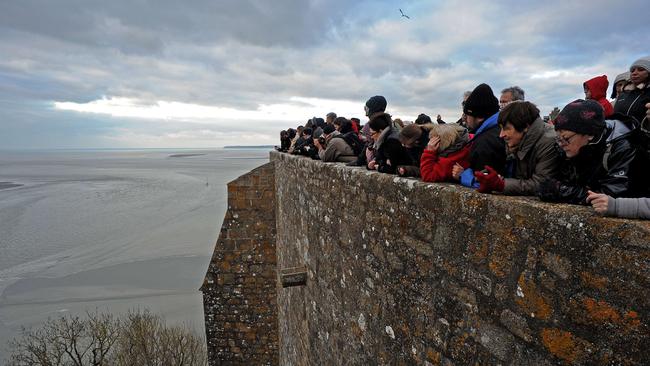 People wait watching for the wave named ‘Mascaret’ in front of the abbey church on the top of the Mont-Saint-Michel, on March 21. Pic: AFP/Guillaume Souvant