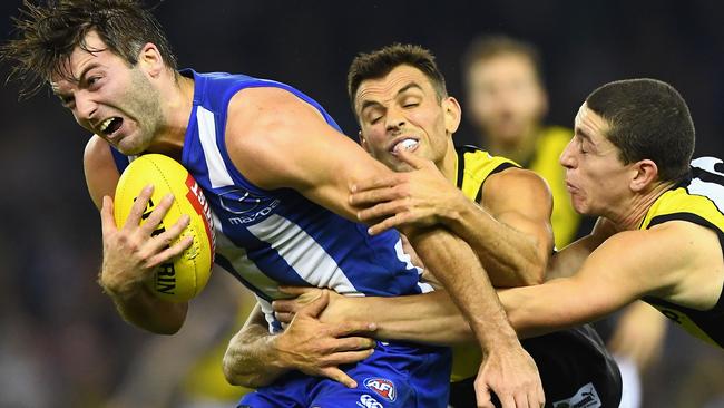 Luke McDonald is brought down by Tigers Sam Lloyd and Jason Castagna.