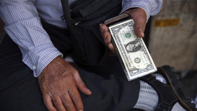 An Iranian street money exchanger holds U.S. banknote in downtown Tehran, Iran, Monday, July 30, 2018. Iran's currency has dropped to a record low ahead of the imposition of renewed American sanctions, with many fearing prolonged economic suffering or possible civil unrest. (AP Photo/Vahid Salemi)