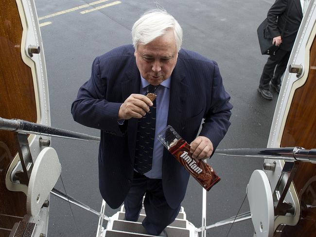 Palmer United Party (PUP) leader Clive Palmer eats Tim Tams as he boards his plane in Hobart, Friday, Aug. 30, 2013.  (AAP Image/Dave Hunt) NO ARCHIVING
