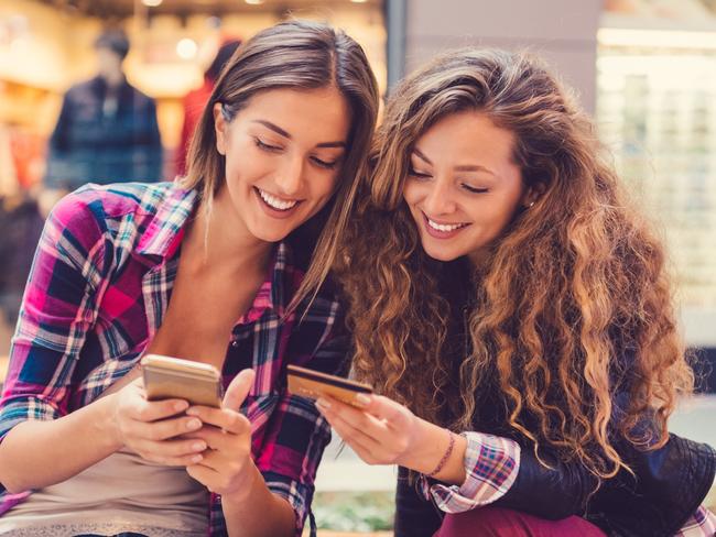 Young women in the mall using credit card for online shopping +++++ Note for the inspector : Credit card is fake and made especially for the photosession +++++ i stock image