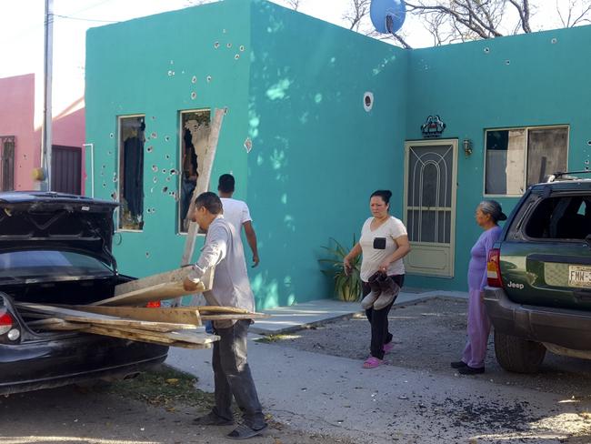 Residents stand in front of a home riddled with bullet holes after a gunbattle between Mexican security forces and suspected cartel gunmen, in Villa Union, Mexico. Picture: AP