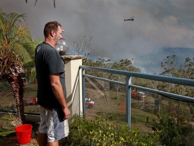 Mr Hopkins watches fire bombing helicopters drop water near his home. Picture: Toby Zerna