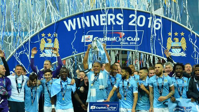 Manchester City's Belgian defender Vincent Kompany (C) holds up the League Cup.