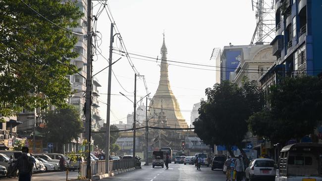 People walk next to the Shwedagon Pagoda on an empty road in Yangon today, after Aung San Suu Kyi and other senior government leaders were detained in early Monday morning raids. Picture: AFP