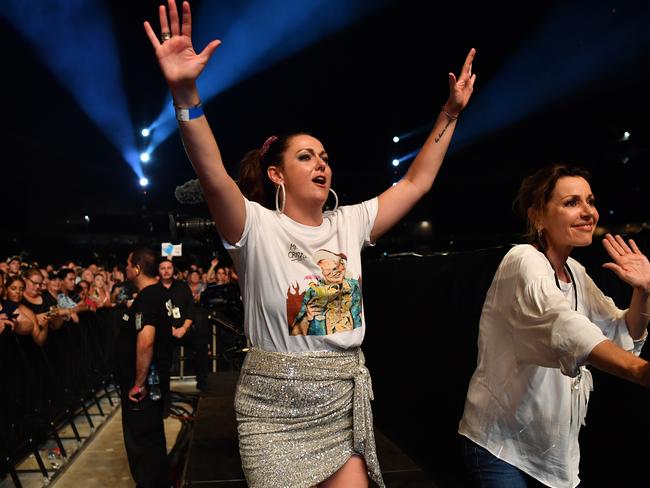 Celeste Barber (left) wearing a shirt featuring Prime Minister Scott Morrison and Tina Arena dance along to John Farnham during the Fire Fight Australia bushfire relief concert. Picture: AAP