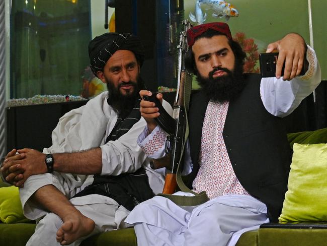 Taliban fighters take a selfie with a mobile phone inside the mansion. Picture: AFP