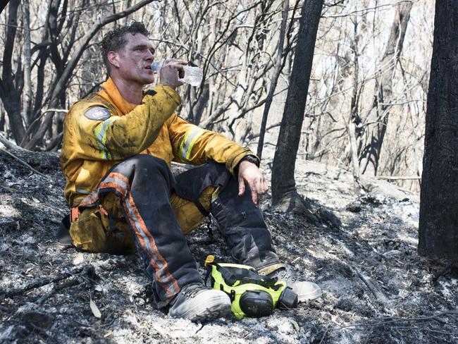 Tasmania Fire Service firefighter Simon Pilkington at the Gell River fire. A soft bed of ash and a spot under some brush is the only refuge when the weather reading showed 38C in the shade. Picture: WARREN FREY/TASMANIA FIRE SERVICE