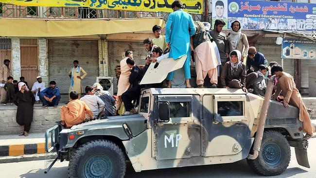 Taliban fighters and local residents sit over an Afghan National Army (ANA) humvee vehicle along the roadside in Laghman province. Picture: AFP