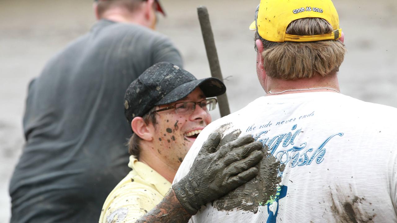 An army of people from Gold Coast businesses pitch in with mud up to their knees to clean out a property on Avebury St, West End. (L-R) Dave Jeffrey gives Mark Hobbs a pat on the back.