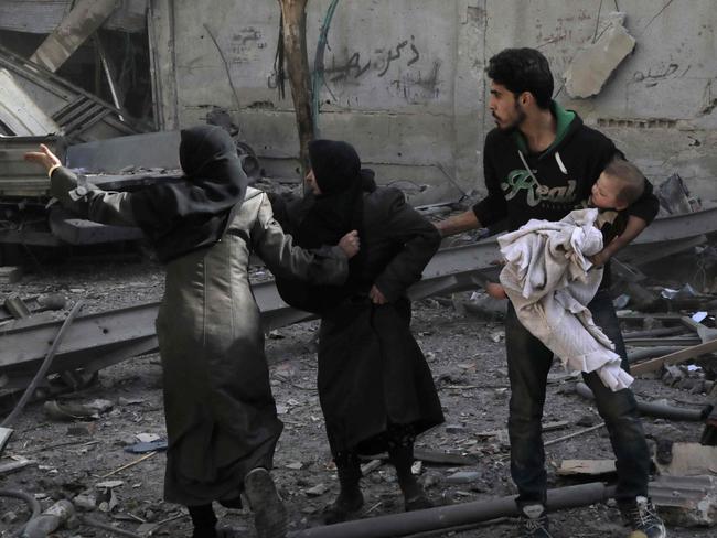 TOPSHOT - Syrians run for cover following Syrian government air strikes on the Eastern Ghouta rebel-held enclave of Douma, on the outskirts of the capital Damascus on March 20, 2018. Syrian regime and allied forces battled to suppress the last pockets of resistance in and around Damascus while the beleaguered Kurds in the north braced for further Turkish advances. Assad has in recent months brought swathes of territory back under his control thanks to heavy Russian involvement, as well as support from other forces such as the Iran-backed Lebanese Hezbollah militia. Eastern Ghouta's main town of Douma remains under rebel control but even as a trickle of emergency medical evacuations was scheduled to continue, the regime continued to pound the enclave. / AFP PHOTO / HAMZA AL-AJWEH