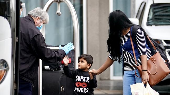 A child high fives the bus driver on his way out of quarantine with his mother. Photo: MIKE BURTON