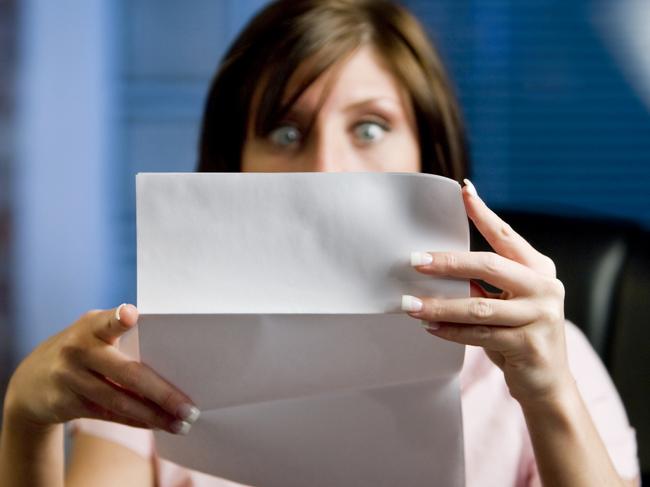 A woman looking at her mail (letter or bills)  in disbelief, shock!