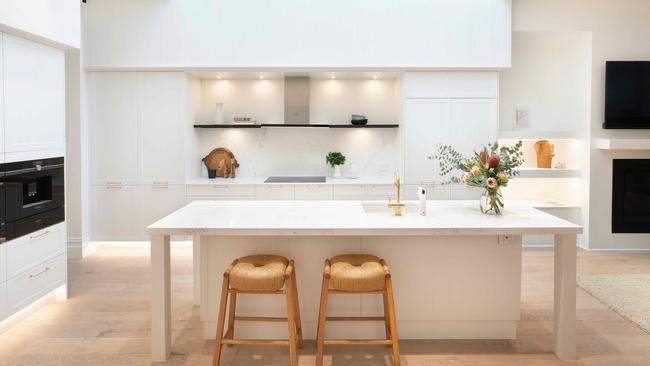 This all-white kitchen has dashes of warmth in the bar stools and flooring.