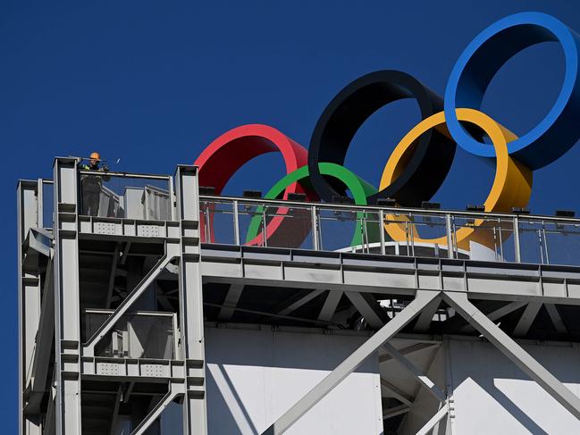 A worker paints a part of a building where the Olympic Rings are located in Shougang Park, one of the sites for the Beijing 2022 Winter Olympics, in December 1, 2021. (Photo by Noel Celis / AFP)