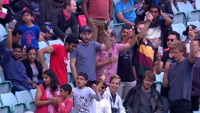 Disgruntled SCG fans use their phone lights to brighten the field.