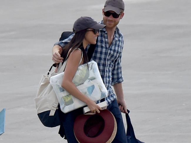 Prince Harry and Meghan Markle walking along the runway at the airport in Africa.