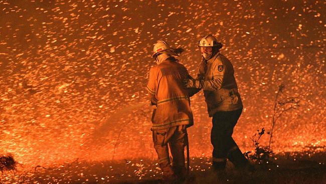 Firefighters struggle against strong winds in an effort to secure nearby houses from bushfires near the NSW south coast town of Nowra in 2019. Picture: AFP