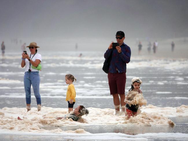 A family playing in sea foam at Burleigh Heads as the wet weather continues in QLD.   Picture: Alex Coppel.