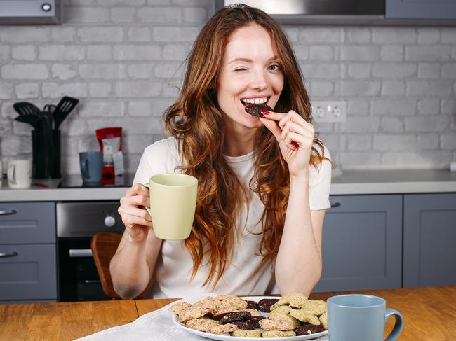 Woman eating cookie and drinking milk. Cute adorable beautiful young female model.  istock image