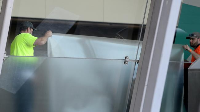 Workers fit frosted screens at MCEC ahead of the conference. Picture: Andrew Henshaw