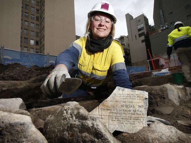 Senior archaeologist Cornelia de Rochefort with a section of the Herald newspaper stuck to stonework dating back to the early 1900s. Picture: David Caird