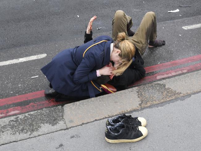 A woman assist an injured person on Westminster Bridge in London. Picture: Reuters