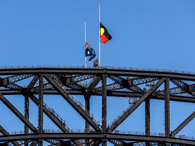 Flags atop the Sydney Harbour Bridge fly at half-mast as a mark of respect for the victims. Picture: David Gray/AFP