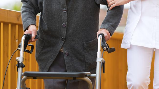 Elderly man using a walking frame in aged care. Generic photo.