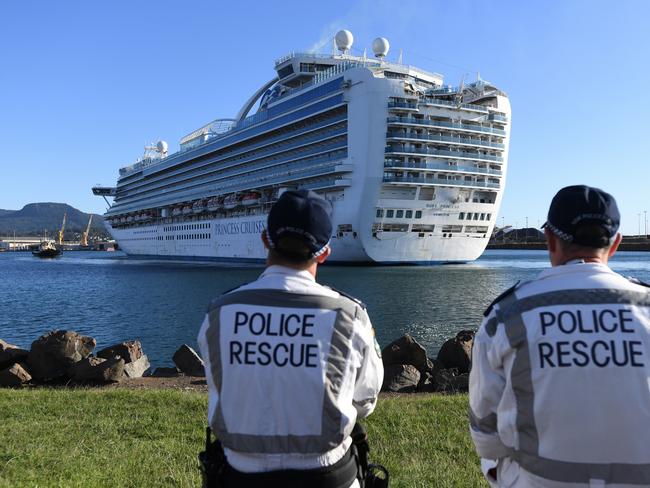 EMBARGO FOR TWAM 2 MAY FEE APPLIES NSW Police Rescue officers look  on as the Ruby Princess, with crew only onboard, docks at Port Kembla, Wollongong, Monday, April 6, 2020. A criminal investigation will be launched into how cruise line operator Carnival Australia was allowed to disembark Ruby Princess passengers in Sydney, resulting in several deaths and COVID-19 outbreaks throughout the country. (AAP Image/Dean Lewins) NO ARCHIVING