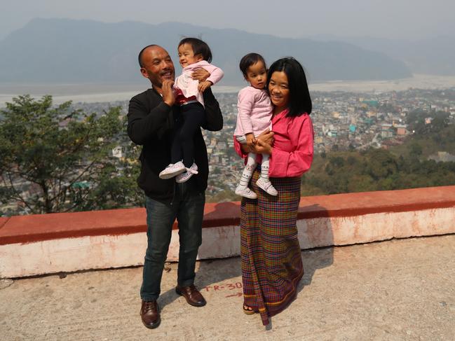 Dad Sonam holds Dawa while mum Bhumchu holds Nima at a lookout overlooking Phuntsholing mountains. Picture: Alex Coppel