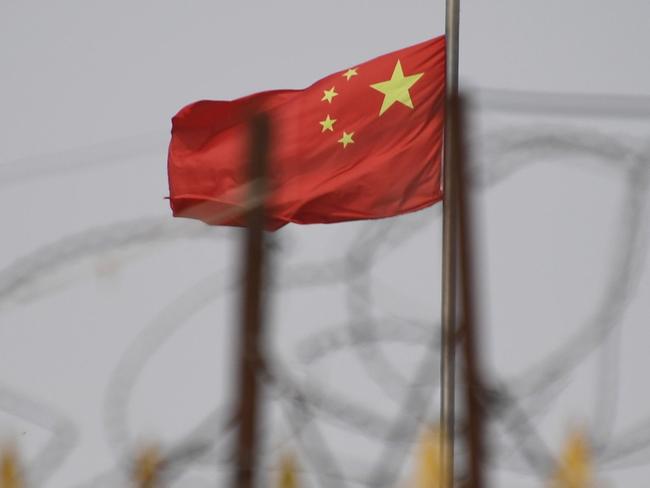 TOPSHOT - This photo taken on June 4, 2019 shows the Chinese flag behind razor wire at a housing compound in Yangisar, south of Kashgar, in China's western Xinjiang region. - A recurrence of the Urumqi riots which left nearly 200 people dead a decade ago is hard to imagine in today's Xinjiang, a Chinese region whose Uighur minority is straitjacketed by surveillance and mass detentions. A pervasive security apparatus has subdued the ethnic unrest that has long plagued the region. (Photo by GREG BAKER / AFP)