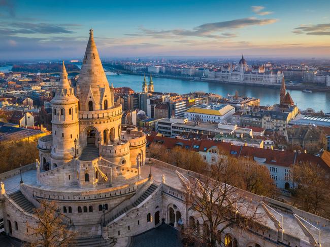 Budapest, Hungary - The main tower of the famous Fisherman's Bastion (Halaszbastya) from above with Parliament building and River Danube at background on a sunny morning