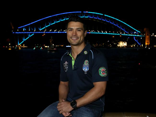 pic of former Origin star, Craig Wing with the bridge and city bathed in blue. With  the minister Stuart Ayres