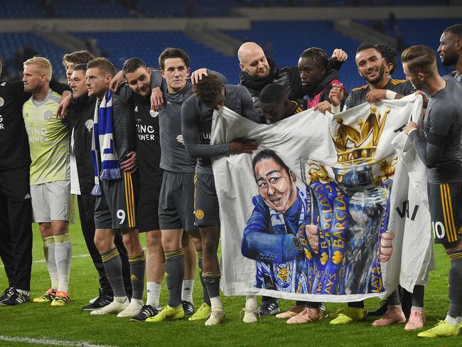 Leicester City's English midfielder James Maddison (R) and Leicester City's English midfielder Demarai Gray (6R) hold a banner showing Leicester City Chairman Vichai Srivaddhanaprabha holding the Premier League Cup following the English Premier League football match between between Cardiff City and Leicester City at Cardiff City Stadium in Cardiff, south Wales on November 3, 2018. (Photo by Oli SCARFF / AFP) / RESTRICTED TO EDITORIAL USE. No use with unauthorized audio, video, data, fixture lists, club/league logos or 'live' services. Online in-match use limited to 120 images. An additional 40 images may be used in extra time. No video emulation. Social media in-match use limited to 120 images. An additional 40 images may be used in extra time. No use in betting publications, games or single club/league/player publications. /