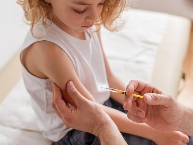 Close-up of a sweet blond boy and a doctor with a syringe