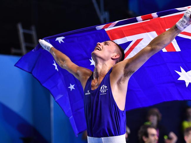 Australia's Harry Garside holds his national flag after beating India's Manish Kaushik in their men's 60kg final boxing match during the 2018 Gold Coast Commonwealth Games at the Oxenford Studios venue on the Gold Coast on April 14, 2018. / AFP PHOTO / Anthony WALLACE