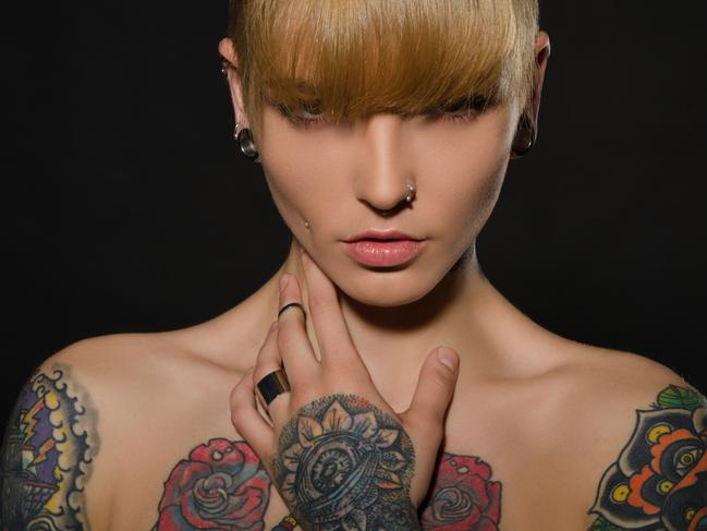 Beautiful blonde with a tattoo on body, dark background . iStock