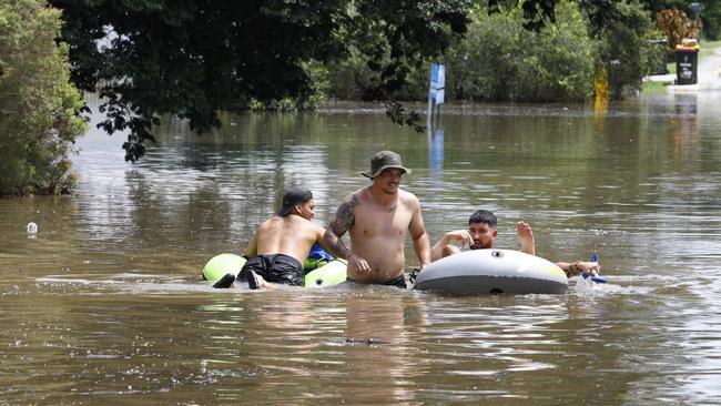 Flooding in Brisbane after heavy rains. Suede Kino, centre, helps Mark Runkovski, right, to safety. Picture: Tertius Pickard