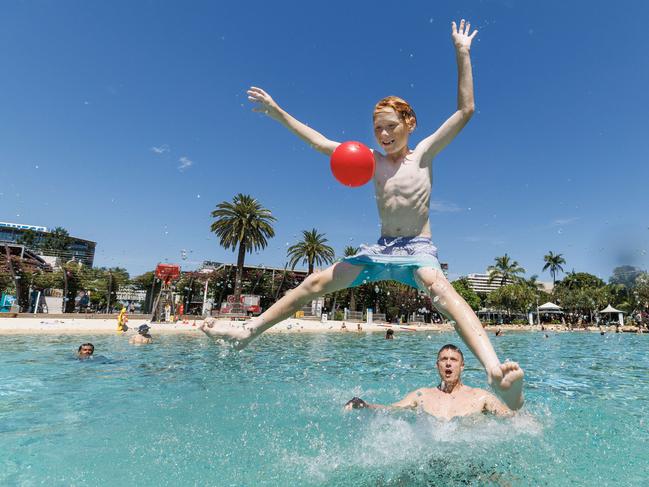 12 year old Jadon Hubble launches from the water with help from dad Matt at Southbank as the summer heat kicks in across Brisbane. Picture: Lachie Millard