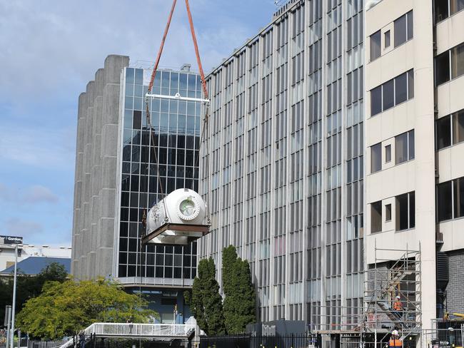 The new hyperbaric chamber is lifted from Collins Street by crane into the Royal Hobart Hospital. Picture: LUKE BOWDEN