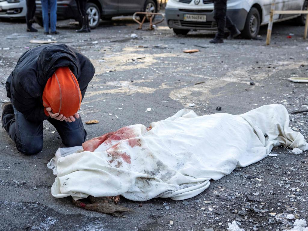 A person mourns next to a wrapped body near a residential building which was hit by the debris from a downed rocket in Kyiv. Picture: AFP