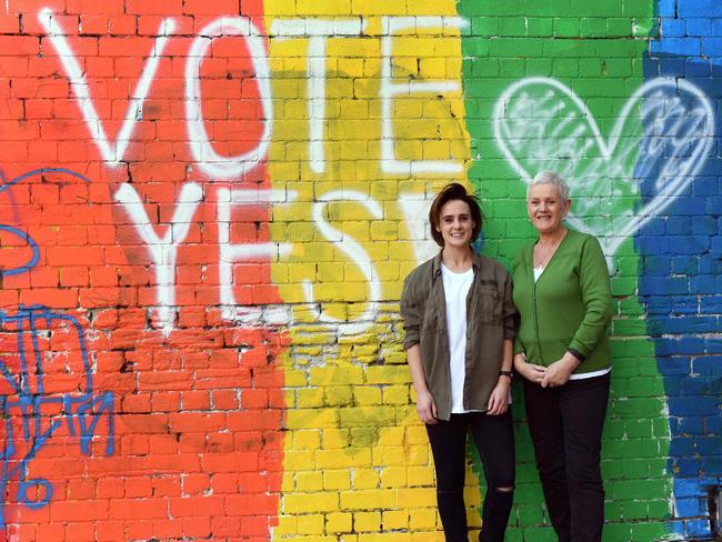 People pose for a photo in front of a Vote Yes mural supporting same-sex marriage in Sydney on September 7, 2017. Australia's High Court on September 7, threw out two challenges to a same-sex marriage postal vote planned by the government, paving the way for a national survey on whether such unions should be legalised. / AFP PHOTO / WILLIAM WEST