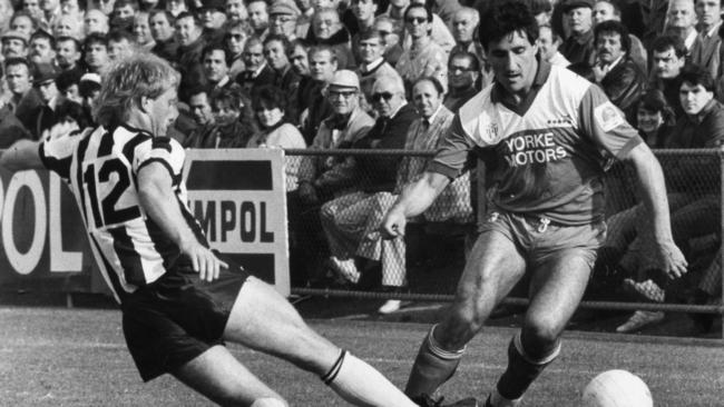 West Adelaide Hellas’ Charlie Yankos is tackled by Adelaide City’s Teddy Maybank during a derby at Hindmarsh Stadium in 1986.
