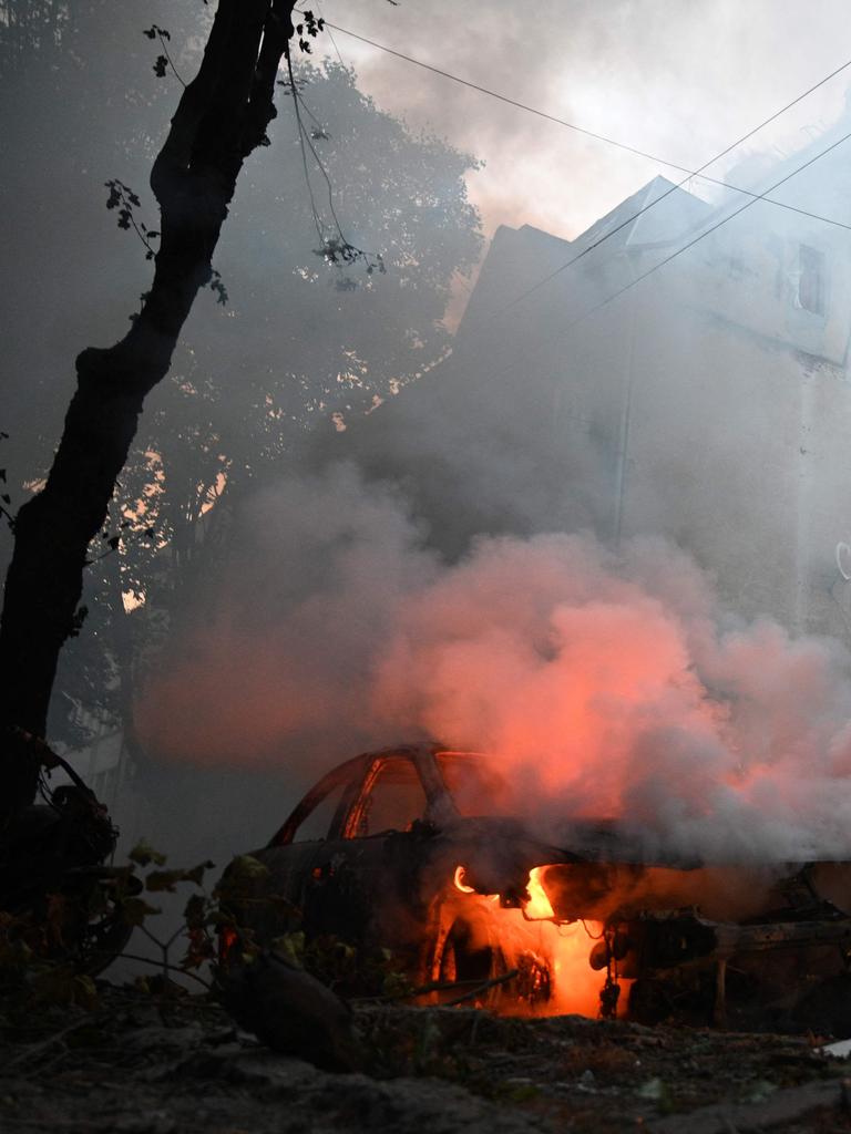 A Ukrainian rescuer works to extinguish a fire in a car following a missile attack in Lviv. Picture: YURIY DYACHYSHYN / AFP