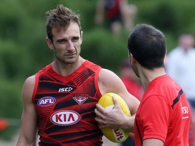 Essendon training at Tullamarine. Jobe Watson talks with club official as they walk off the track .Pic : Michael Klein