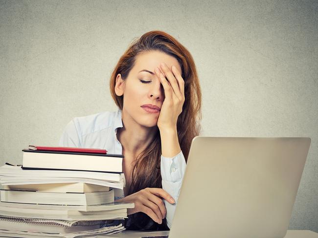 Too much work tired sleepy young woman sitting at her desk with books in front of laptop computer isolated grey wall office background. Busy schedule in college, workplace, sleep deprivation concept