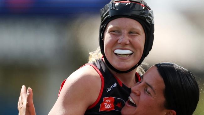 Chloe Adams is all smiles after kicking a goal on debut for Essendon as she’s embraced by teammate Maddy Prespakis. Picture: Will Russell/AFL Photos via Getty Images