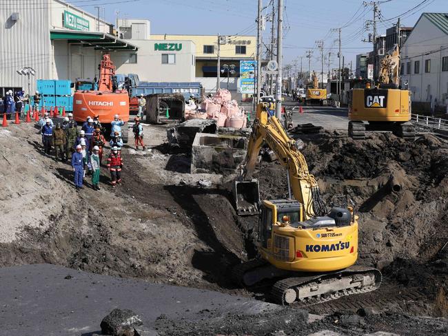 Excavators and rescue personnel working to construct a slope for rescue operations are seen at the site where a truck on January 28 plunged into a sinkhole, trapping the vehicle's driver, in Yashio, Saitama Prefecture on February 1, 2025. Japanese rescuers completed building a slope on February 1 to reach a truck driver stuck in a sinkhole, officials said, four days after his vehicle was swallowed by the cavity now 40 metres wide. (Photo by JIJI PRESS / AFP) / Japan OUT