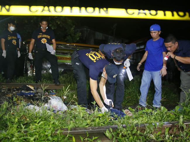Police officers inspect the body of a person killed in a sting operation. Picture: AP Photo/Bullit Marquez.
